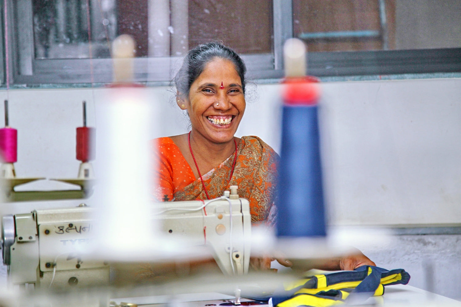 EcoRight artisans skillfully sewing eco-friendly bags with a big smile, focus on quality and sustainable craftsmanship